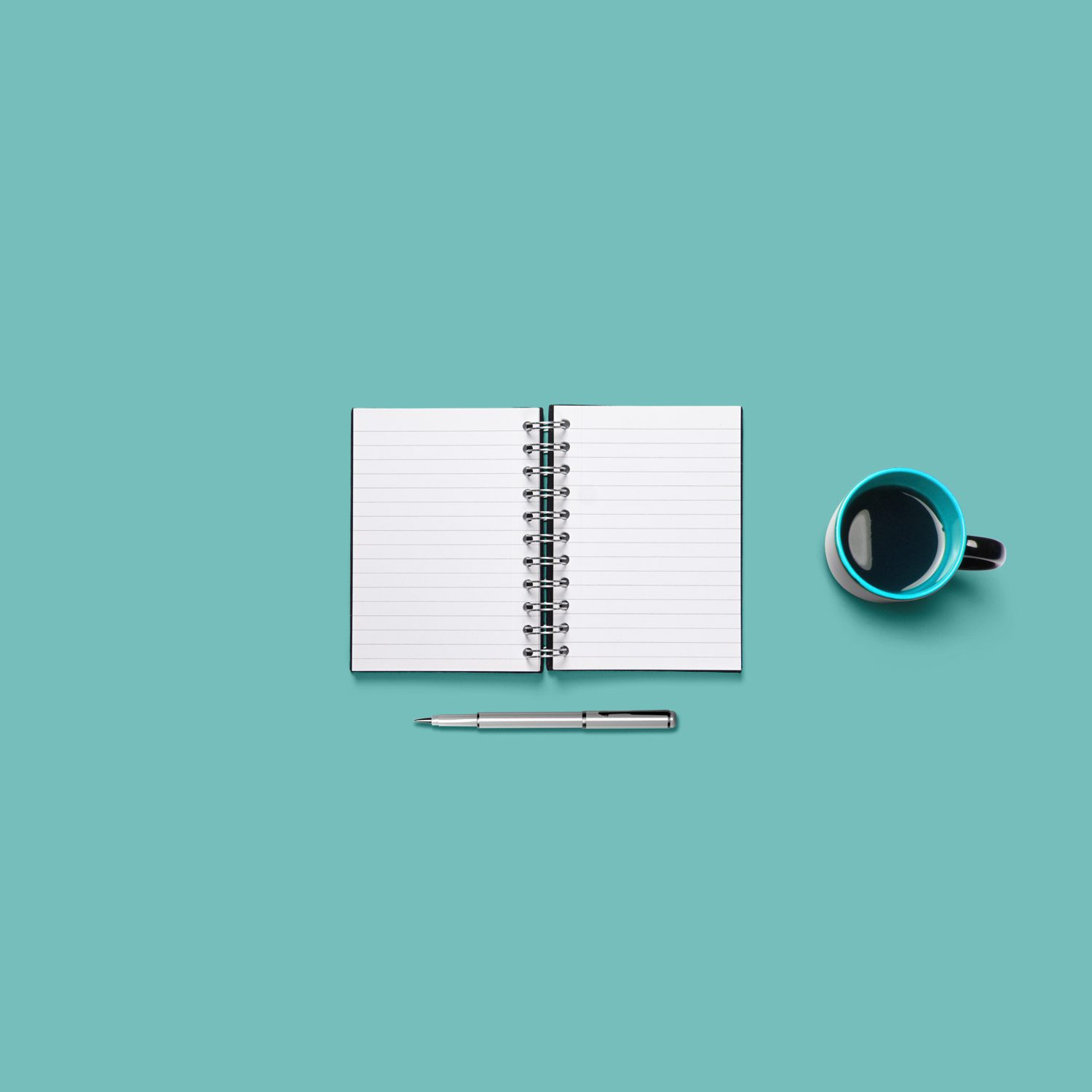 A coffee cup and notebook on a table.
