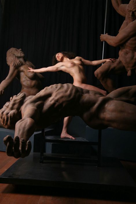 A man is standing naked in front of some statues.