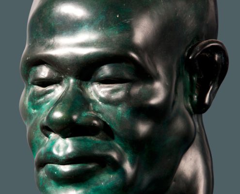 A green statue of a man 's head.