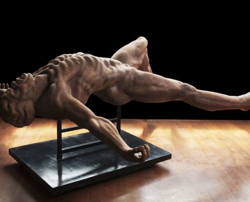 A sculpture of a man stretching on top of a table.