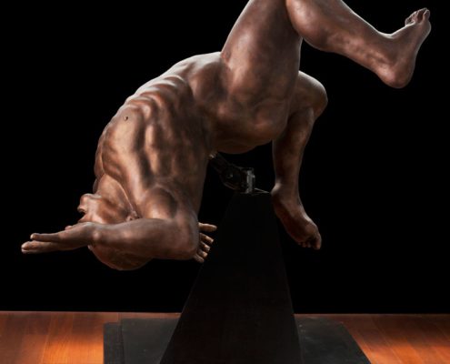 A statue of a man doing a handstand on top of a table.