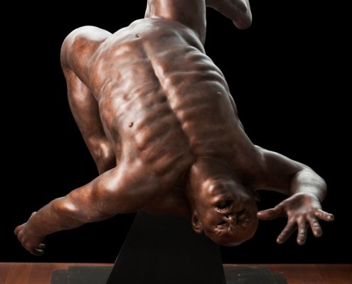 A bronze statue of a man falling down.