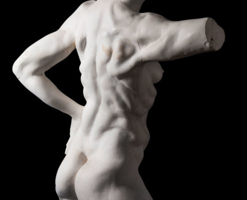 A white statue of a man with his hands on the back.