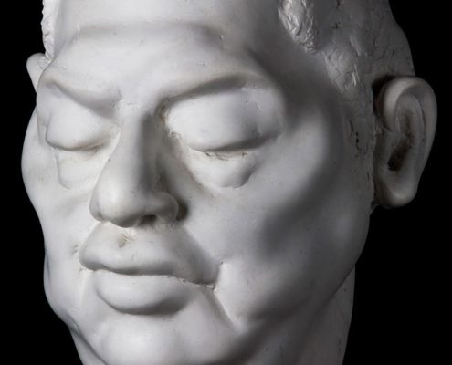 A white statue of a man 's head with his eyes closed.