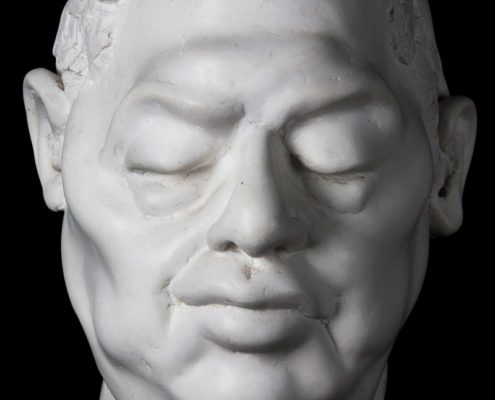 A white statue of a man 's face with eyes closed.