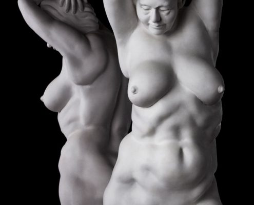 Two white statues of women are standing in a black background.