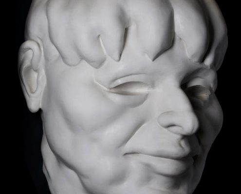 A white statue of a man 's face with his head turned to the side.