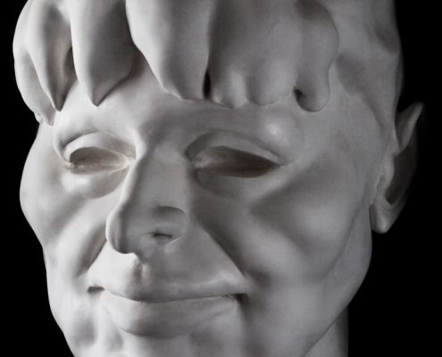 A white statue of a man 's face with the head turned to the side.