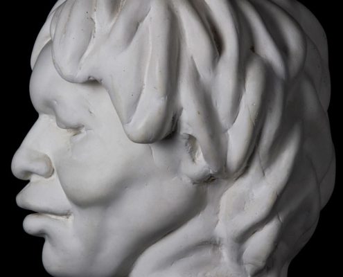 A white statue of a man 's head with long hair.