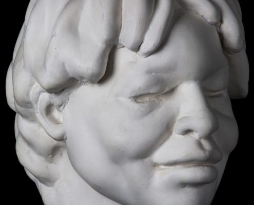 A white statue of a young man 's head.