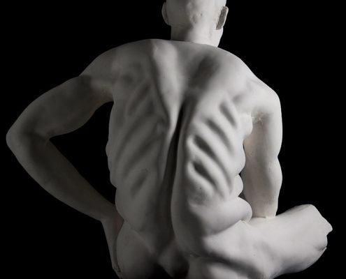 A white statue of a man with his hands on the back.