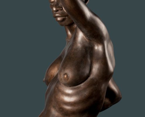 A bronze statue of a woman with her arm raised.