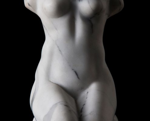 A white statue of a woman with no clothes on.