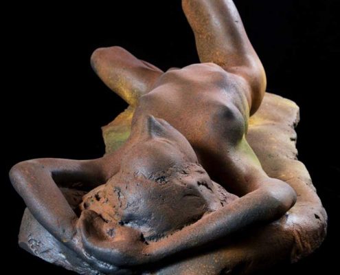 A sculpture of a woman laying on her stomach.