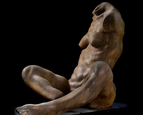 A sculpture of a naked woman sitting on the ground.