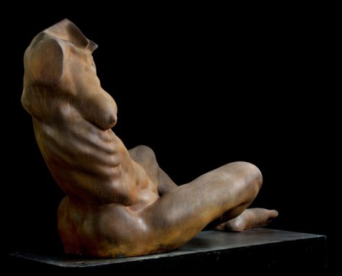 A statue of a naked woman sitting on the ground.