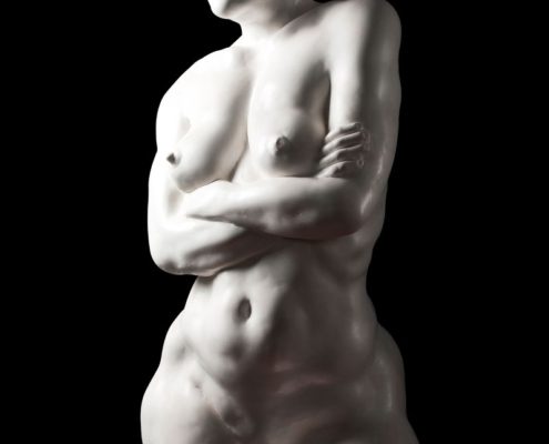 A naked woman standing with her arms crossed.