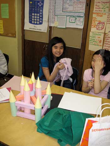 Two girls sitting at a table with candles on top of them.