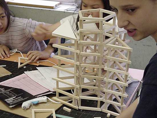 A woman is building a tower out of wood.