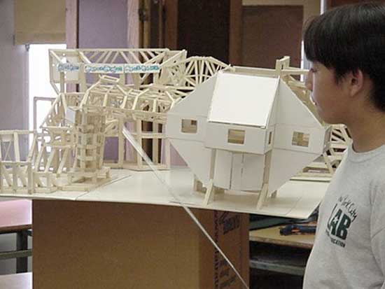 A boy looking at some model buildings in the process of construction.