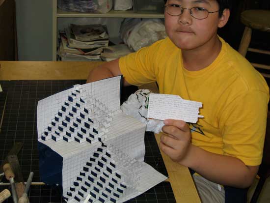 A boy holding paper and looking at it.