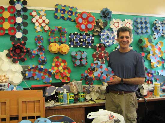 A man standing in front of a wall covered with paper flowers.