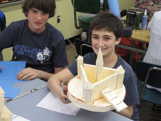 Two boys sitting at a table with paper mache.