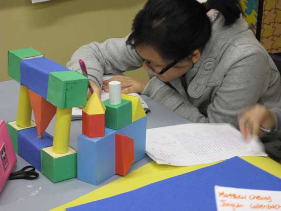 A woman sitting at the table with blocks and papers.