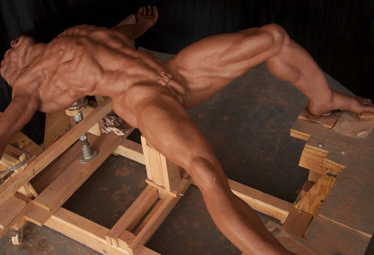 A muscular man is stretching on wooden blocks.