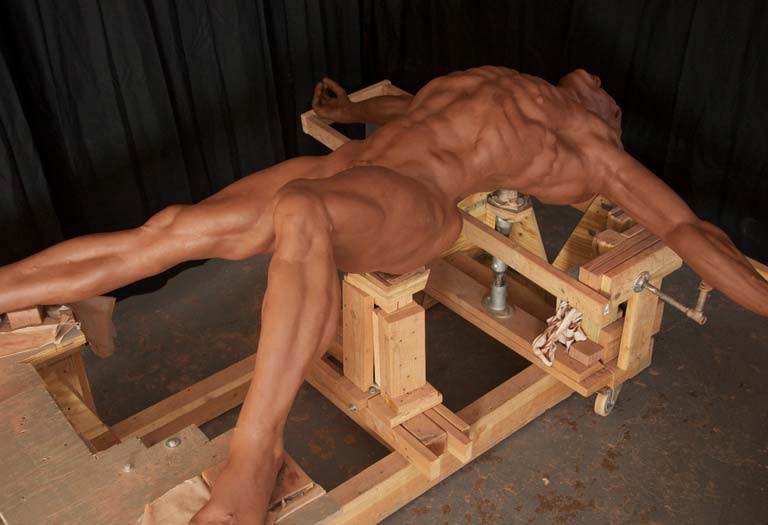 A man is laying on the ground in front of wooden blocks.