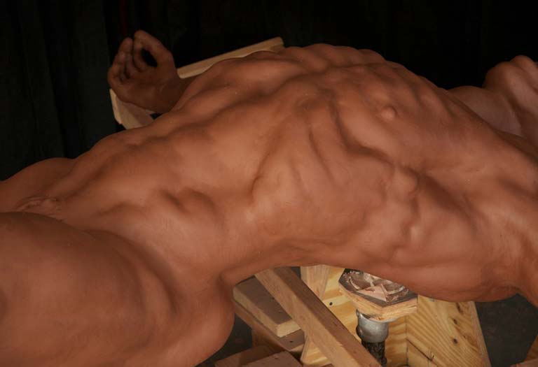 A muscular man is laying down on the ground.