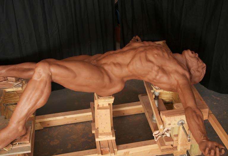 A man with huge muscles is sitting on some wood.