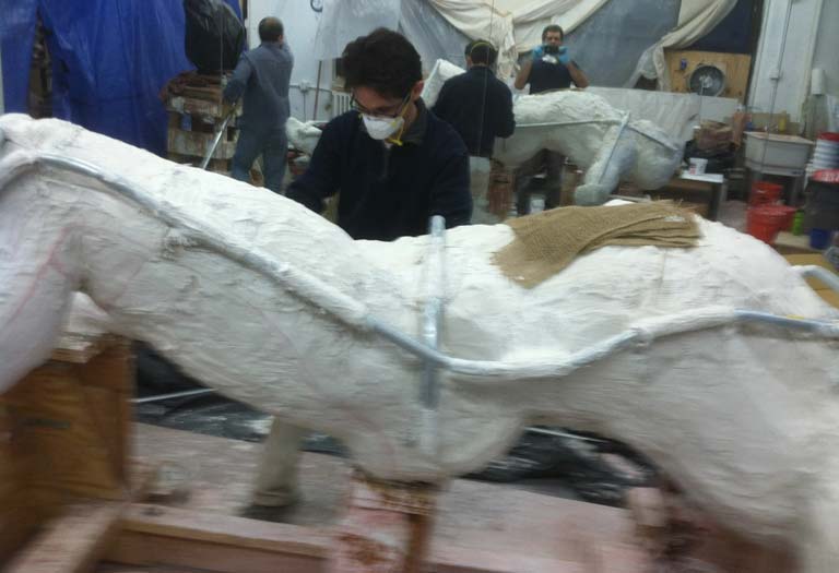 A man standing next to a white dinosaur.