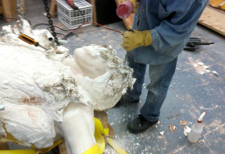 A man in yellow gloves is working on a statue.