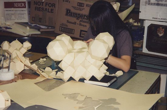 A woman sitting at a table with many white objects.