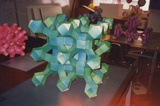 A green and blue paper sculpture sitting on top of a table.