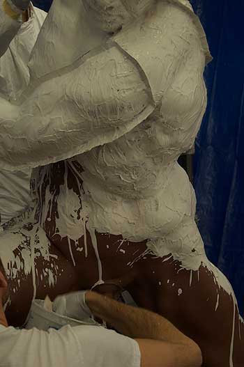 A person covered in white paint and mud.