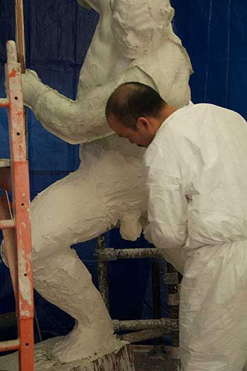 A man in white coveralls working on something.