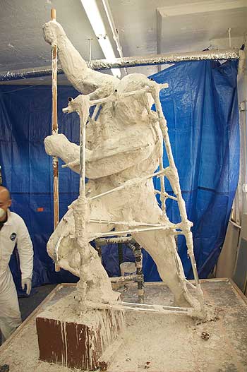 A man in white overalls standing on top of a ladder.