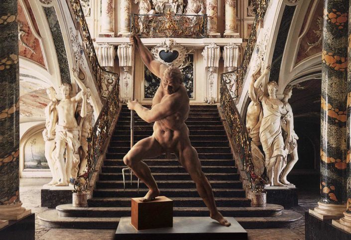 A statue of a man in front of an ornate staircase.