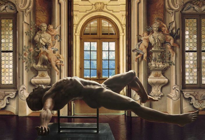 A statue of a man laying on his back in front of an open door.