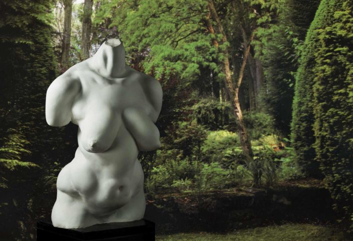 A statue of a woman in the middle of a forest.