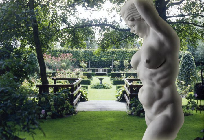 A statue of a woman in the middle of a garden.