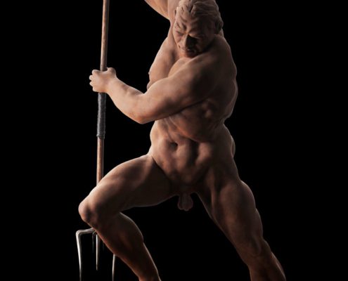 A naked man holding a spear and standing in front of him.